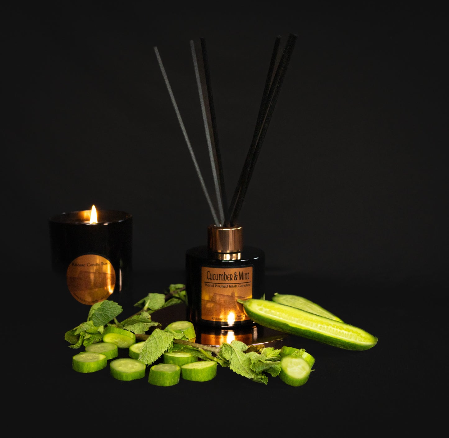 Cucumber-themed diffuser with candles and fresh cucumber slices and mint leaves on a dark background