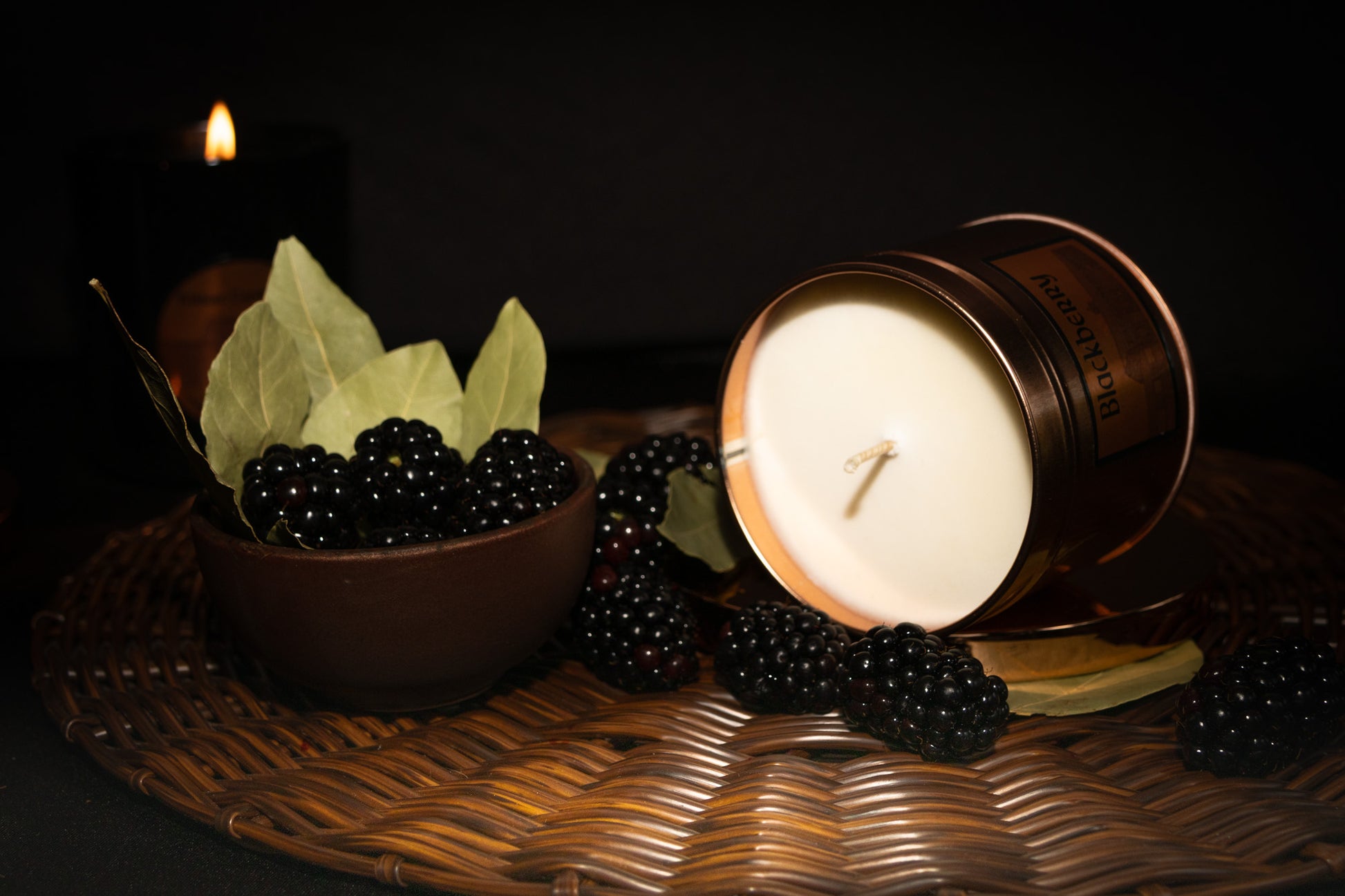 Irish Soy Wax Candle in a copper tin with blackberries and bay leaves on a woven surface