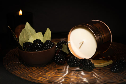 Irish Soy Wax Candle in a copper tin with blackberries and bay leaves on a woven surface