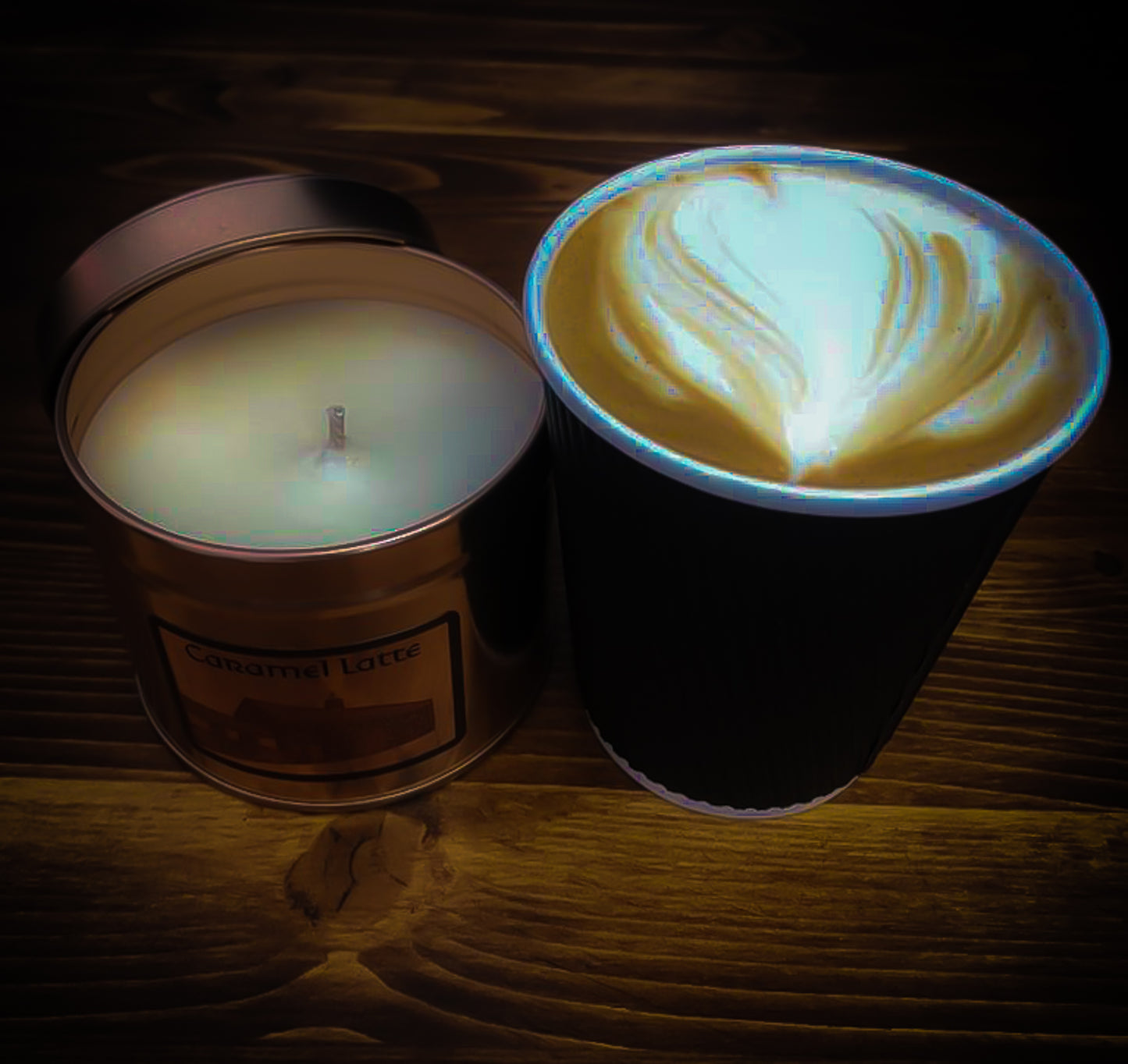 Caramel Latte Irish Soy Wax - Candle in a tin and a cup of coffee with latte art on a wooden surface