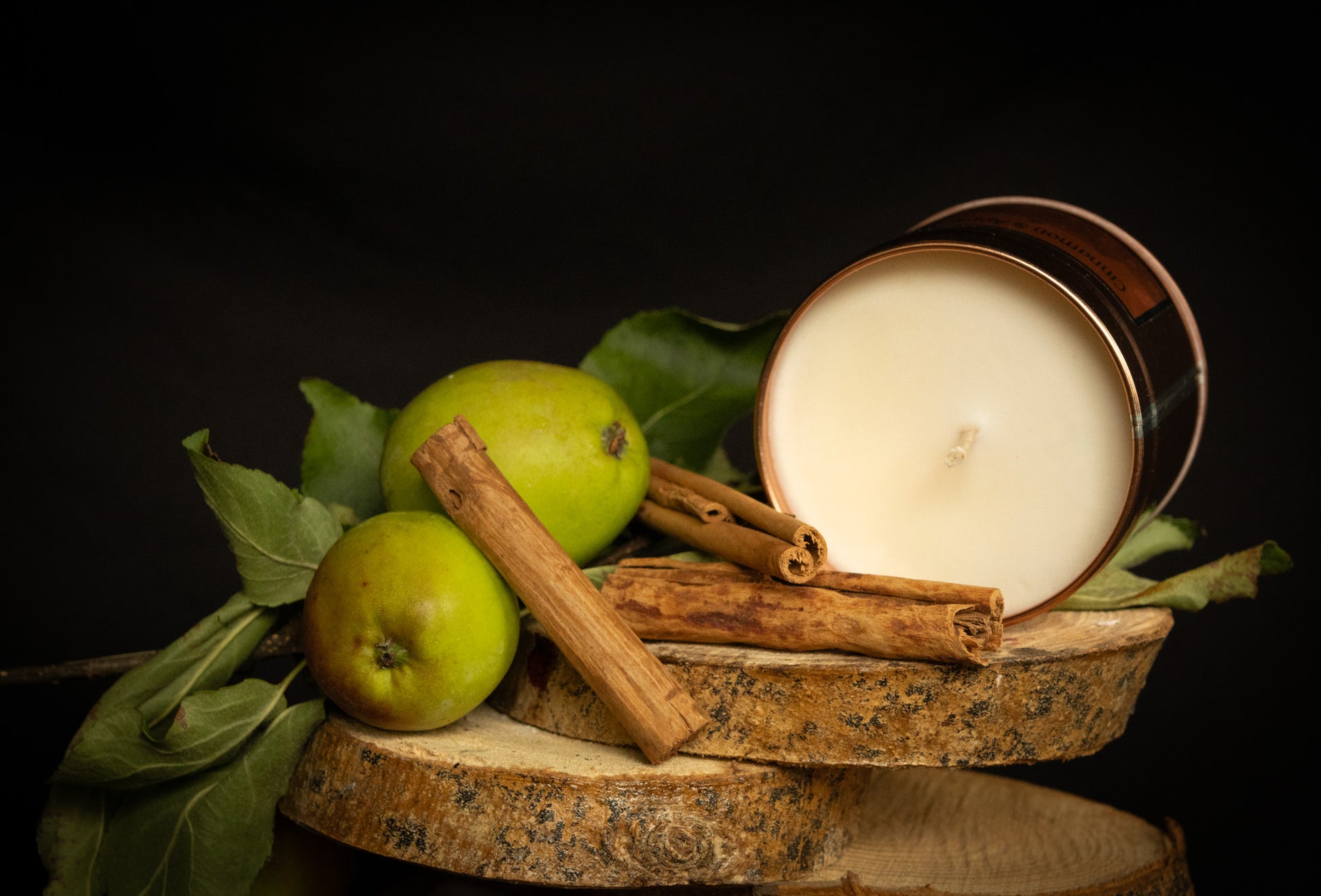 Irish Soy Wax Candle in a copper tin with green apples and cinnamon sticks on a dark background