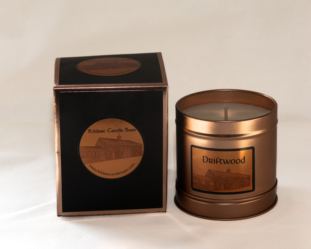 Copper candle with 'Driftwood' branding next to its packaging on a white background