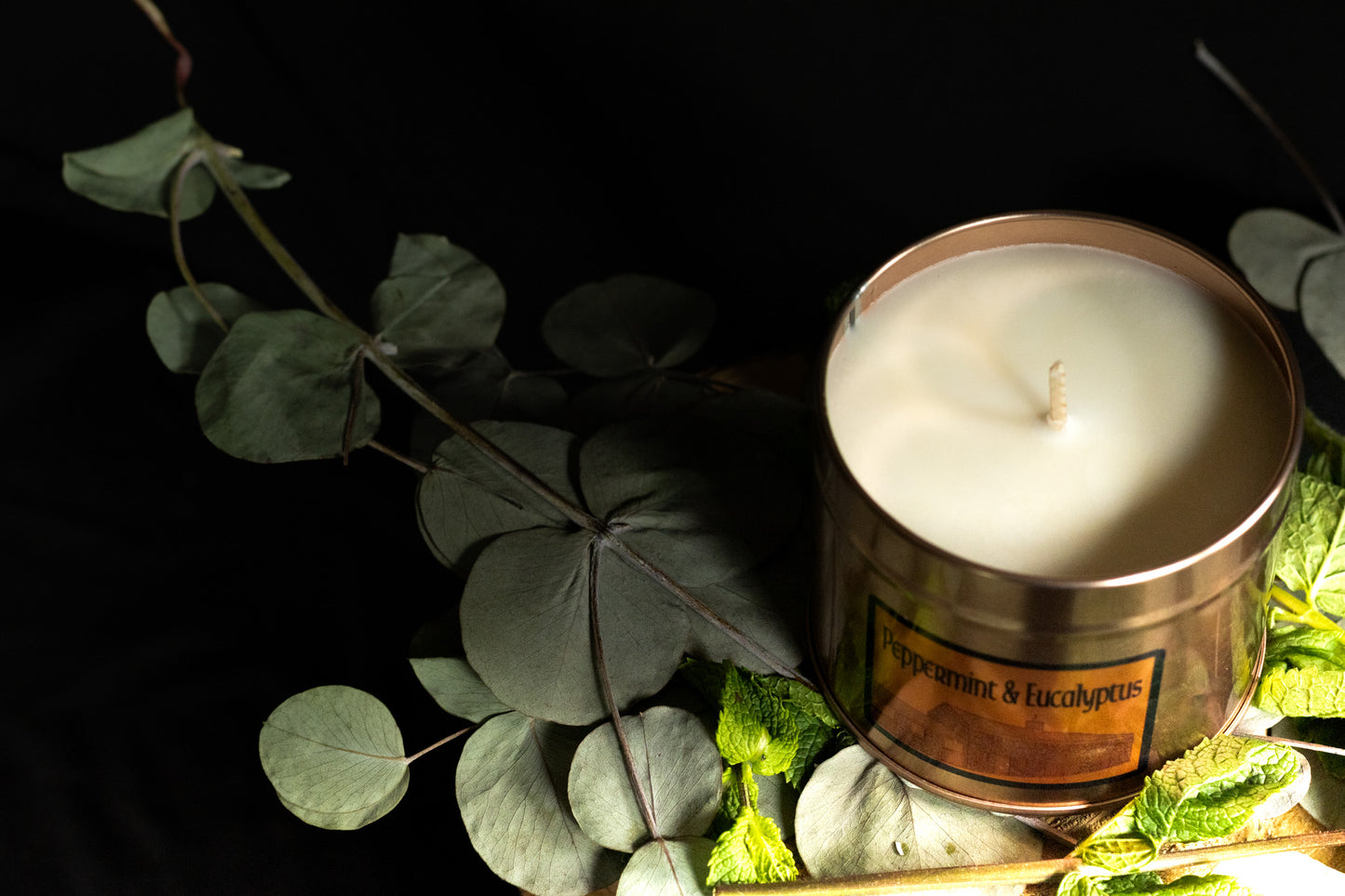 Irish Soy Wax Candle in a decorative container with eucalyptus leaves on a dark background