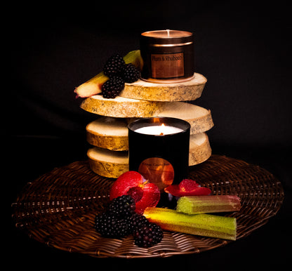 Candle display with various Irish soy wax candles and fruits of plum, rhubarb and blackberry. copper tin and black jar candles.