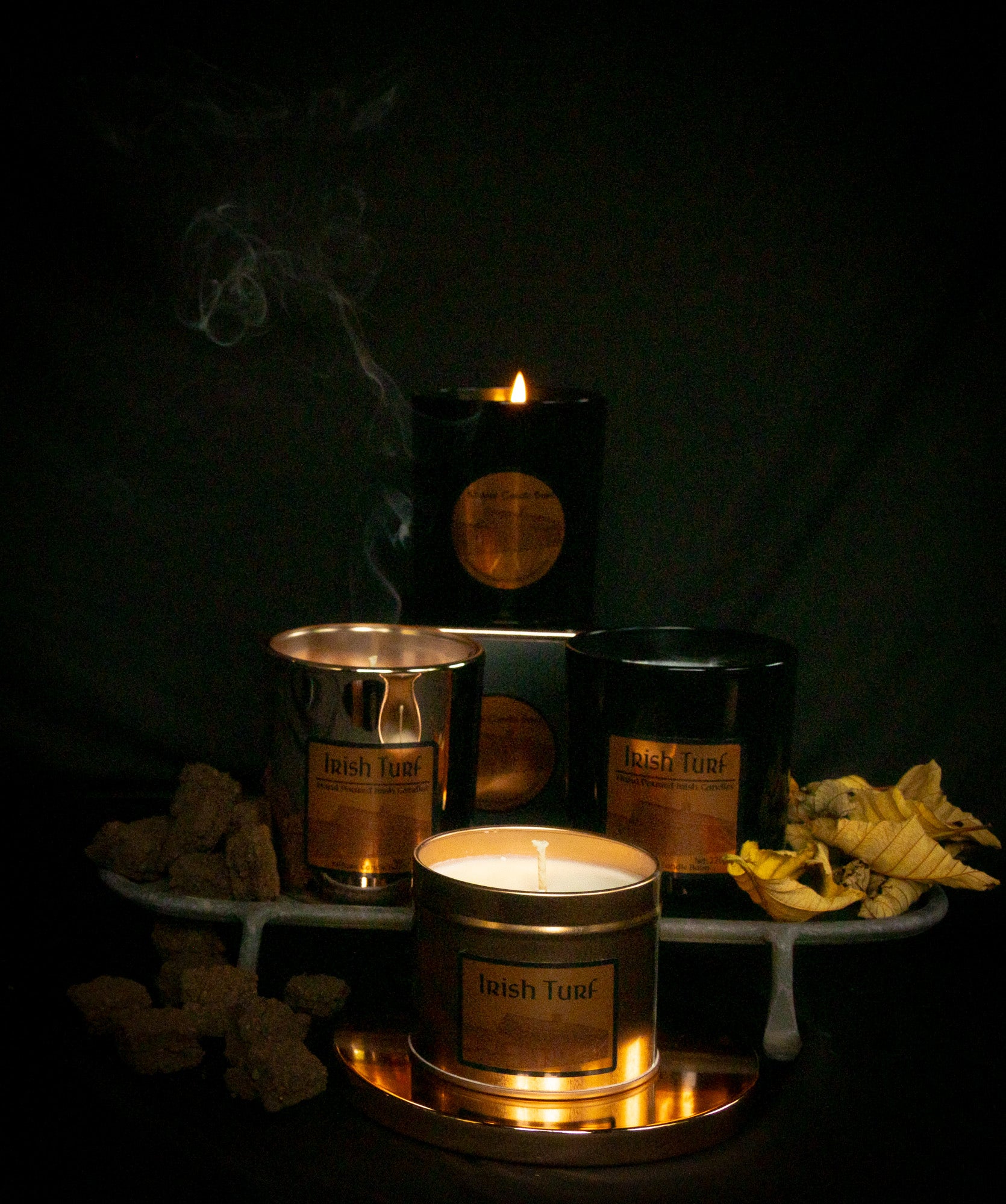 Irish Soy Wax Candles with lit black jar candle with 'Irish Turf' branding on a dark background and smoking turf embers.