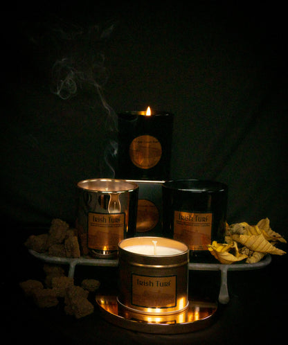 Irish Soy Wax Candles with lit black jar candle with 'Irish Turf' branding on a dark background and smoking turf embers.