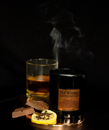Irish Soy Wax Candle in a Black Jar with a Hot whiskey glass with a lemon slice and smoking ambiance on a dark background